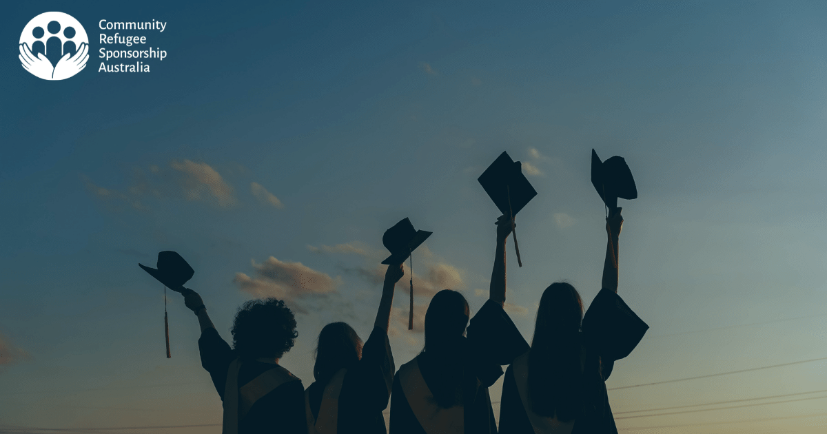 Silhouette of four girls holding graduation caps high in the air